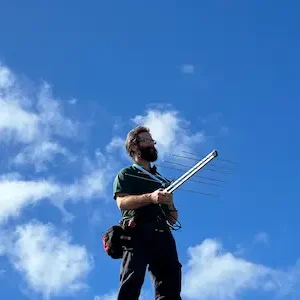 man on roof holding antenna to locate strong TV antenna signal